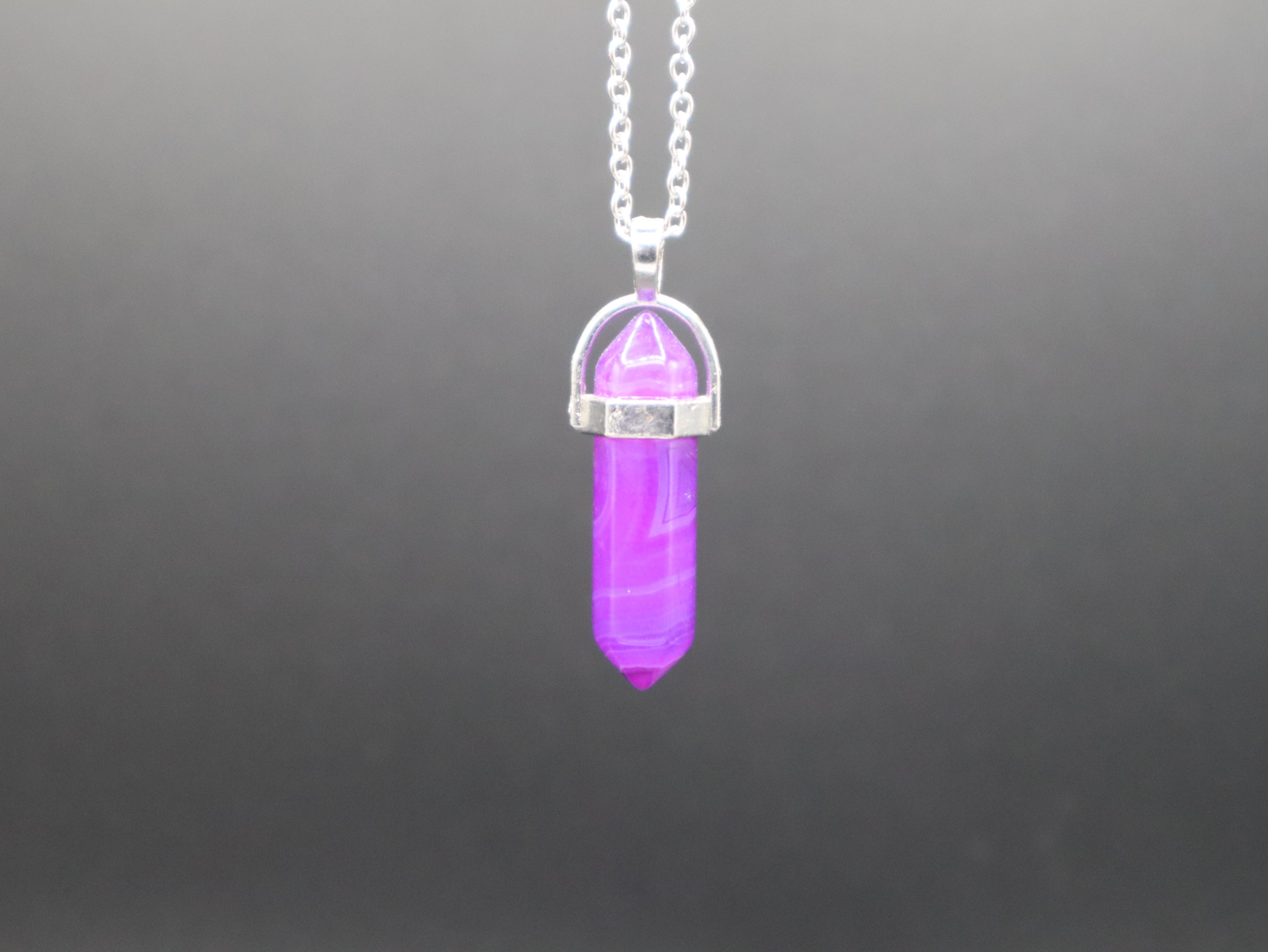 Purple crystal pendant on a silver chain against a gray background