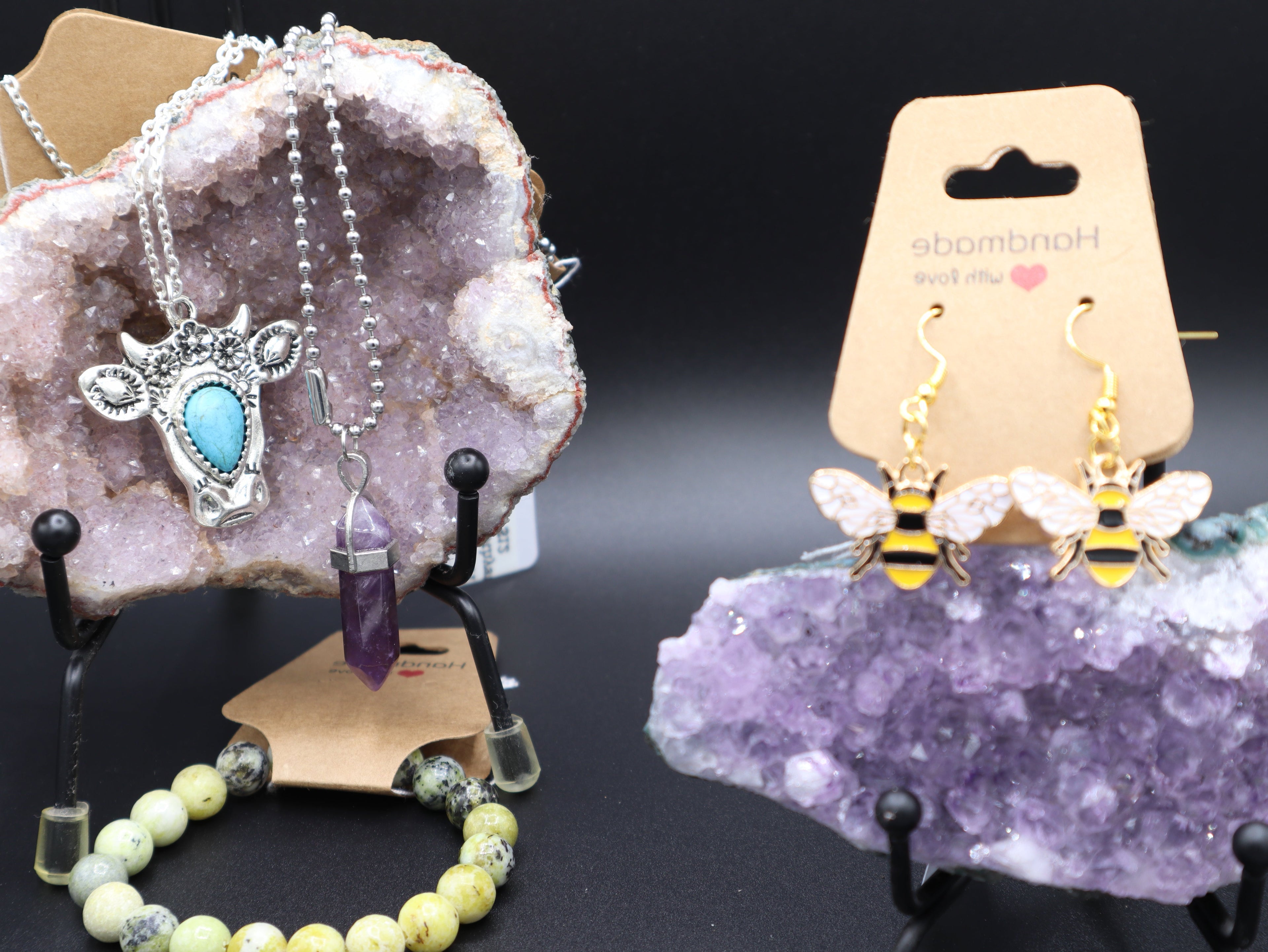 Jewelry set including a necklace, earrings, and bracelet on a dark background with amethyst crystal.
