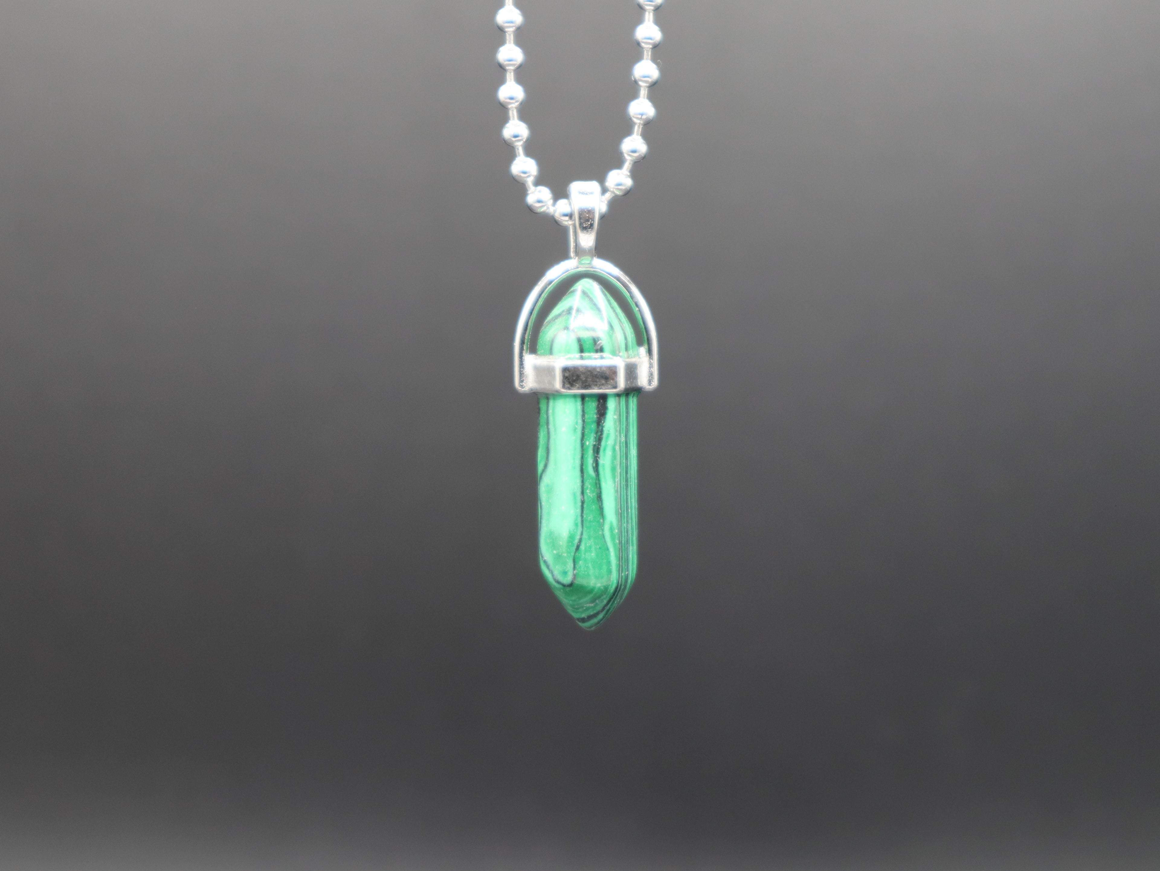 Necklace with a green crystal pendant on a dark gray background